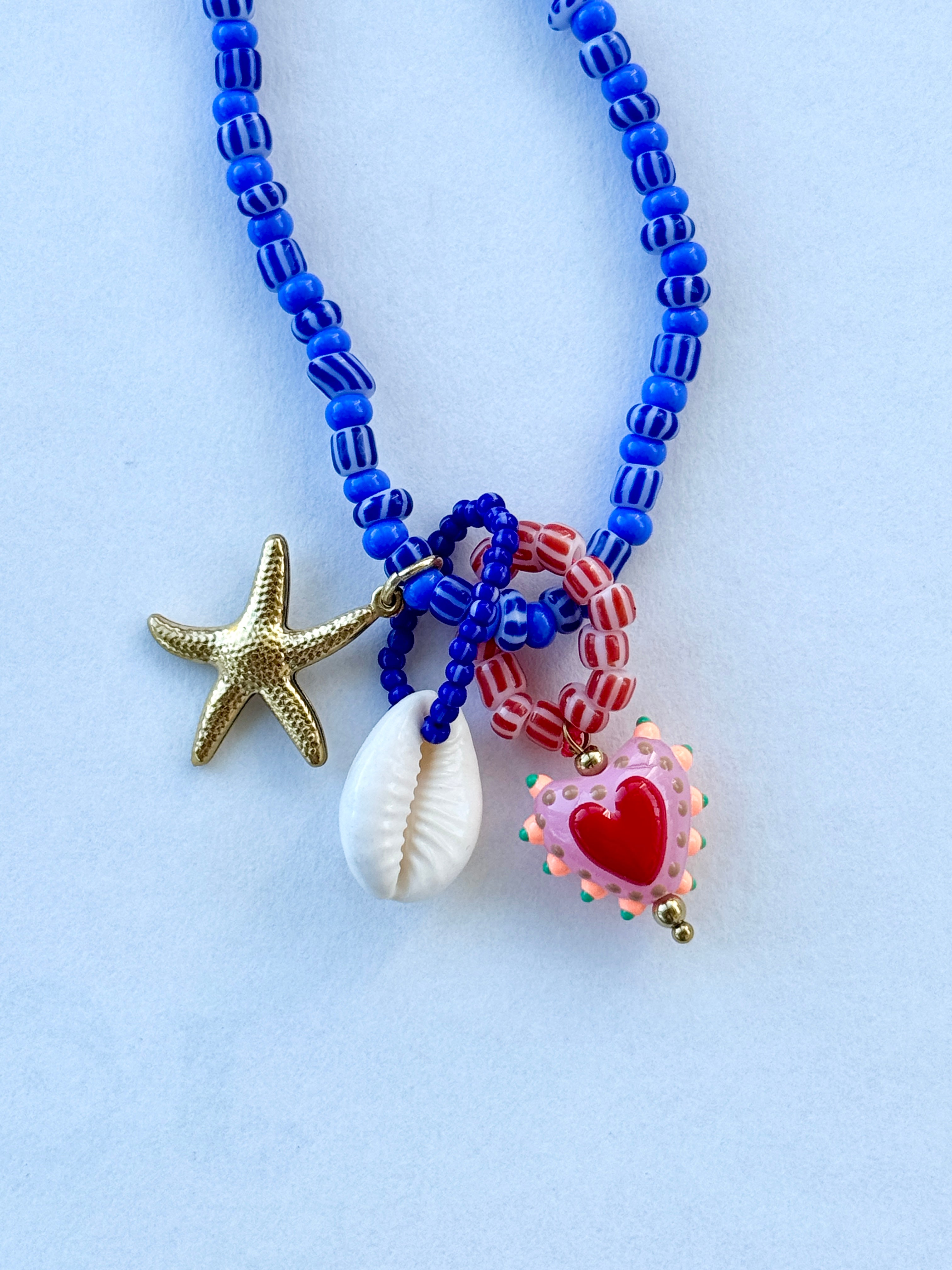 Blue beaded kjede med "Three is a charm"